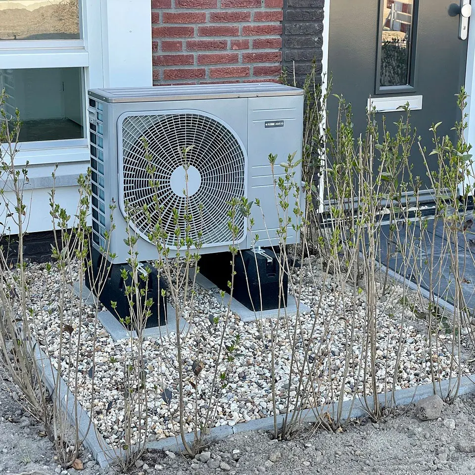 An air source heat pump outside a brick house
