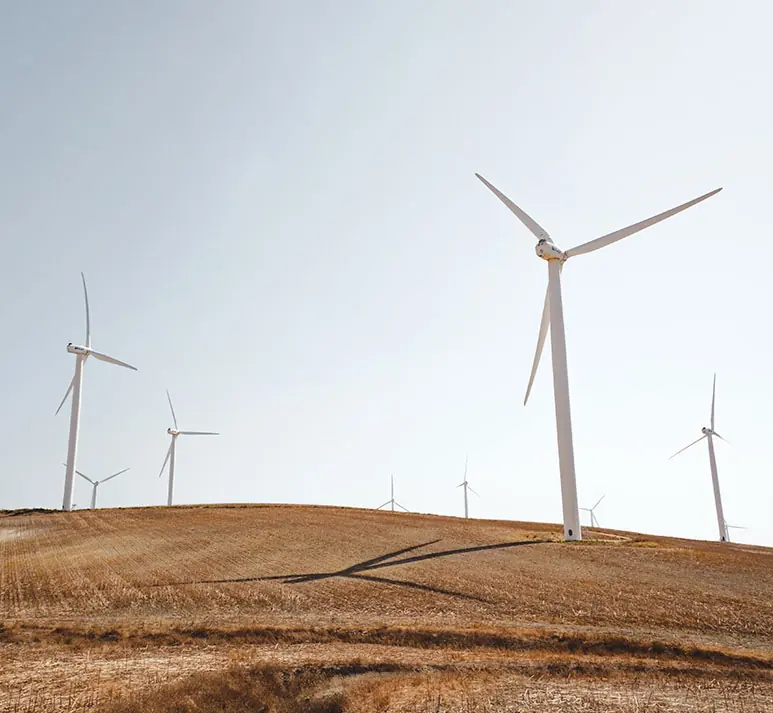 Wind turbines on open farmland under a pale sky